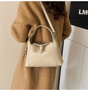Detail view of lychee grain leather underarm bag on a camel coat background