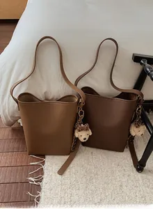 Detail view of large bucket bags in camel and chocolate with teddy bear charms