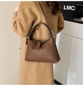 Detail of dark brown lychee leather shoulder bag with buckle and adjustable strap