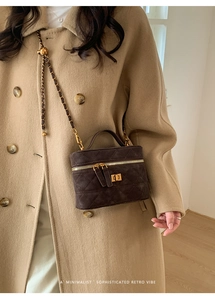 Detail of dark brown suede vanity bag with quilted pattern and gold chain strap