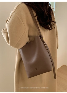 Close-up of litchi grain texture and brand logo on brown leather bucket bag