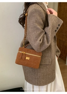 Brown quilted crossbody bag with gold chain strap on a herringbone wool coat model