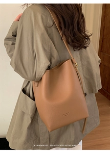 Dettaglio di un'elegante borsa a secchiello marrone a tracolla, con design e texture retrò.