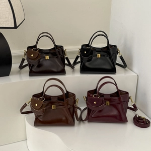 Detail shot of four retro faux leather tote bags in dark tones with gold hardware accents