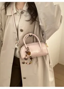Pink mini faux leather handbag with adjustable strap and decorative pompom charm