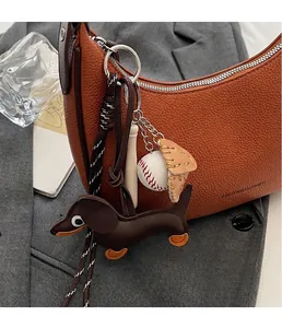 Detail der kreativen Baseball-Anhänger an einer braunen Halbmond-Handtasche aus Leder