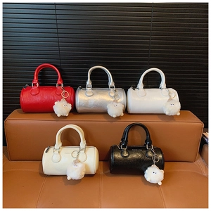 Row of colorful leather barrel bags with plush pompom charms and branded printing