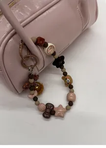 Detail of sweet beaded charm with bear and star icons on a pink Boston leather bag