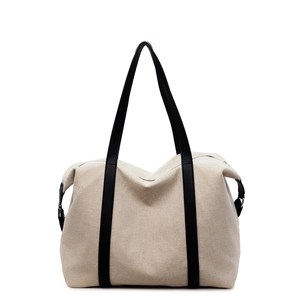 Large beige canvas tote bag with black leather trim and shoulder straps for winter travel