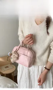 Detail of a pink Boston handbag with cute plush bear charm and sleek zipper closure
