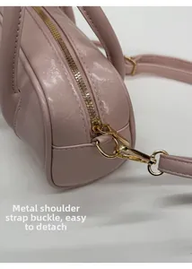 Close-up of detachable gold metal hardware on pink pleated leather Boston bag
