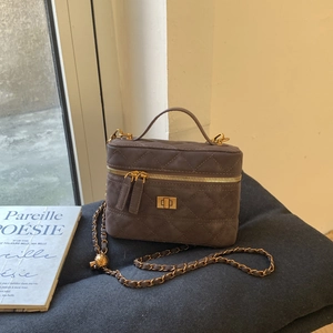 Detail of dark brown quilted leather bag with gold hardware and chain strap