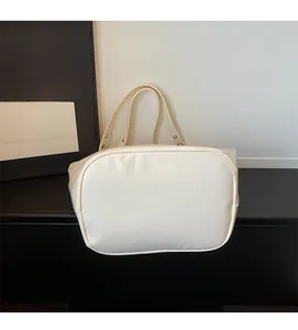 Detail of minimalist white leather tote bag with wide straps and metal rivet accents