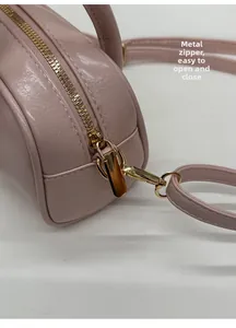 Close-up of metal zipper and leather texture on a pink crossbody pillow bag