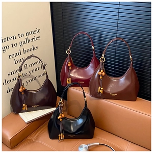 Macro shot of glossy patent leather hobo bags in four colors with bead tassel charms
