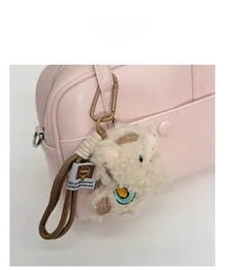 Detailed close-up of light pink pebble leather Boston bag with cute plush animal charm