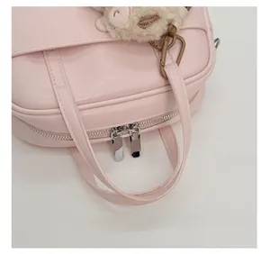 Detail of pink Boston bag featuring dual metal zippers and cute plush animal charm