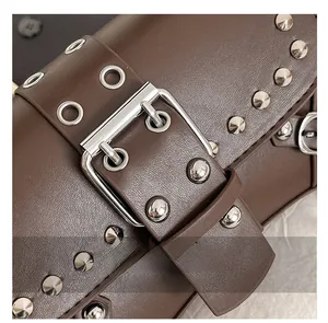 Macro shot of silver studs and buckle on dark brown leather punk style shoulder bag