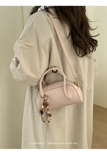 Detailed view of light pink bowling bag with soft leather texture and beaded charm accessory