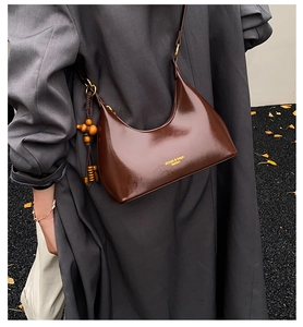 Close-up of deep brown glossy hobo bag with gold hardware and wood bead charm detail