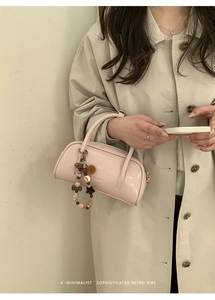 Minimalist light pink square handbag with beaded charm shown on model in beige trench coat