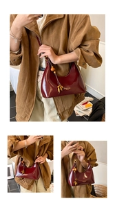 Close-up of deep red oily leather handbag with gold logo and beaded tassel charm