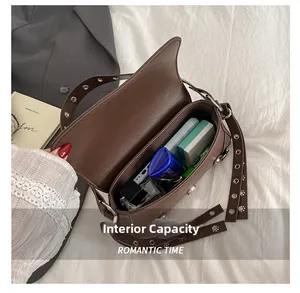 Detail view of large interior capacity for cosmetics in a dark brown rivet handbag