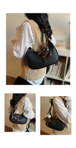 Details der schwarzen Halbmond-Schultertasche mit Dackel- und Baseball-Anhängern