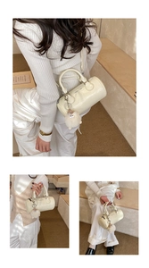 Detail of white cylindrical handbag with plush charm and fashion typography print