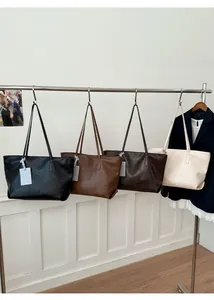 Minimalist large-capacity tote bags in black, brown, and cream hanging on a metal rack
