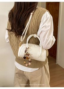 Detail of a chic cream bowling bag with a colorful beaded star charm and slim shoulder strap