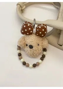 Dettaglio portachiavi barboncino in peluche con anello di perline su borsa