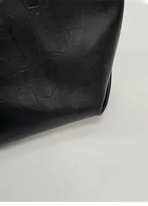 Close-up of matte black leather texture showing high-quality stitching on a tote bag