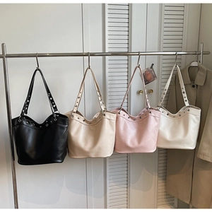 Detail view of large leather tote bags in four colors hanging on a metal rack