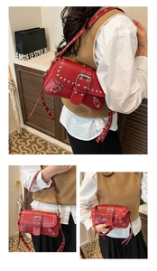 Detailed close-up of red motorcycle bag featuring silver studs and buckle strap details