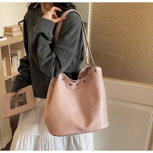Detail of light pink leather tote bag featuring stylish metal eyelets and slim shoulder strap
