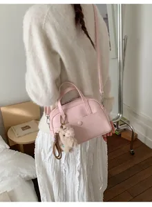 Close-up of pink matte PU leather bucket bag with a cute plush pig keychain accessory