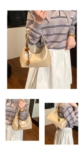 Detailed shot of cream leather underarm bag featuring vintage brown wooden bead charms