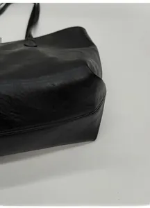 Close-up of wide base and reinforced stitching on a structured black leather tote bag
