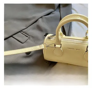 Detail of silver metal hook and pebble grain leather on a cream cylinder bag