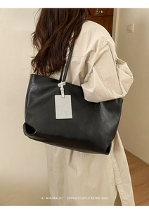 Detail of minimalist black leather tote bag with a white french bulldog embossed tag