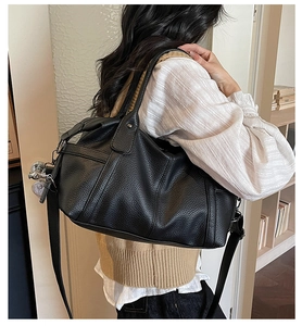 Close-up of black pebble grain leather tote with silver metal hardware and adjustable strap