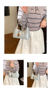 Detail view of light blue patent leather croissant bag with retro wooden bead accessory