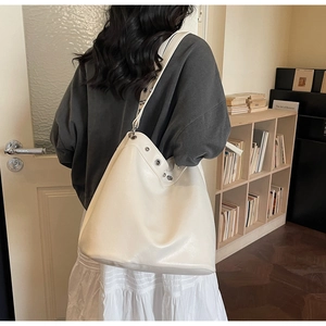 Detail of off-white tote bag with silver metal eyelets and soft leather texture