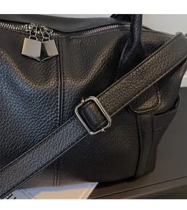 Detail of black litchi grain leather texture and smooth adjustable shoulder strap on tote