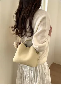 Creamy beige bucket bag styled with a white outfit and cute plush bear accessory