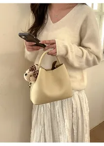Detail of cream leather bucket bag with cute bear charm and polka dot ribbon bow