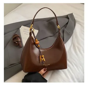 Brown oil leather hobo bag featuring decorative wooden beads and gold branding logo