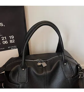 Close-up of black lychee grain leather texture and sturdy handles on large tote bag
