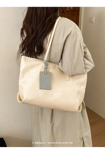 Detail of minimalist cream tote bag showing supple leather texture and cute animal charm